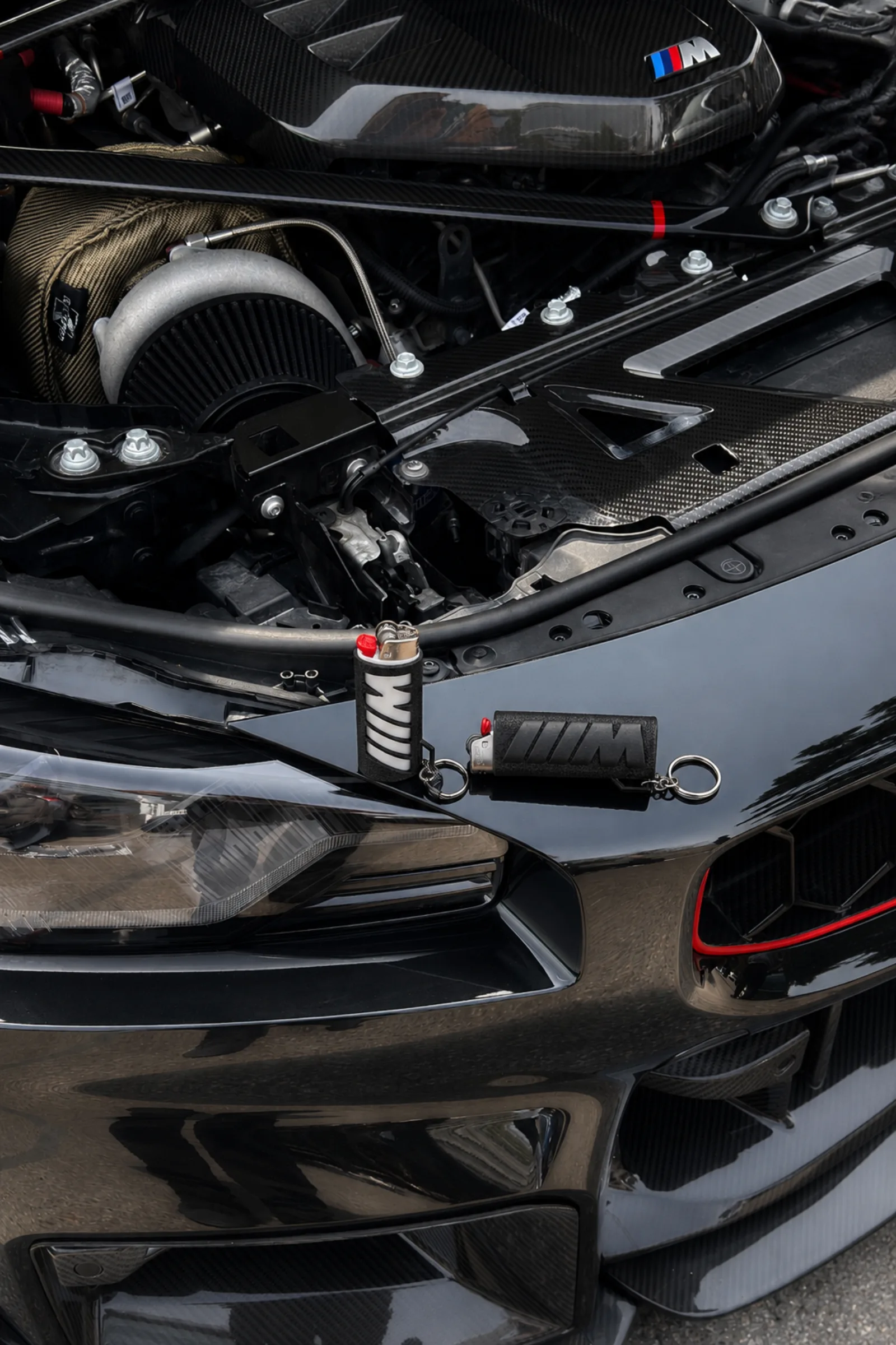 Black and white lighter cases staged on a BMW engine bay