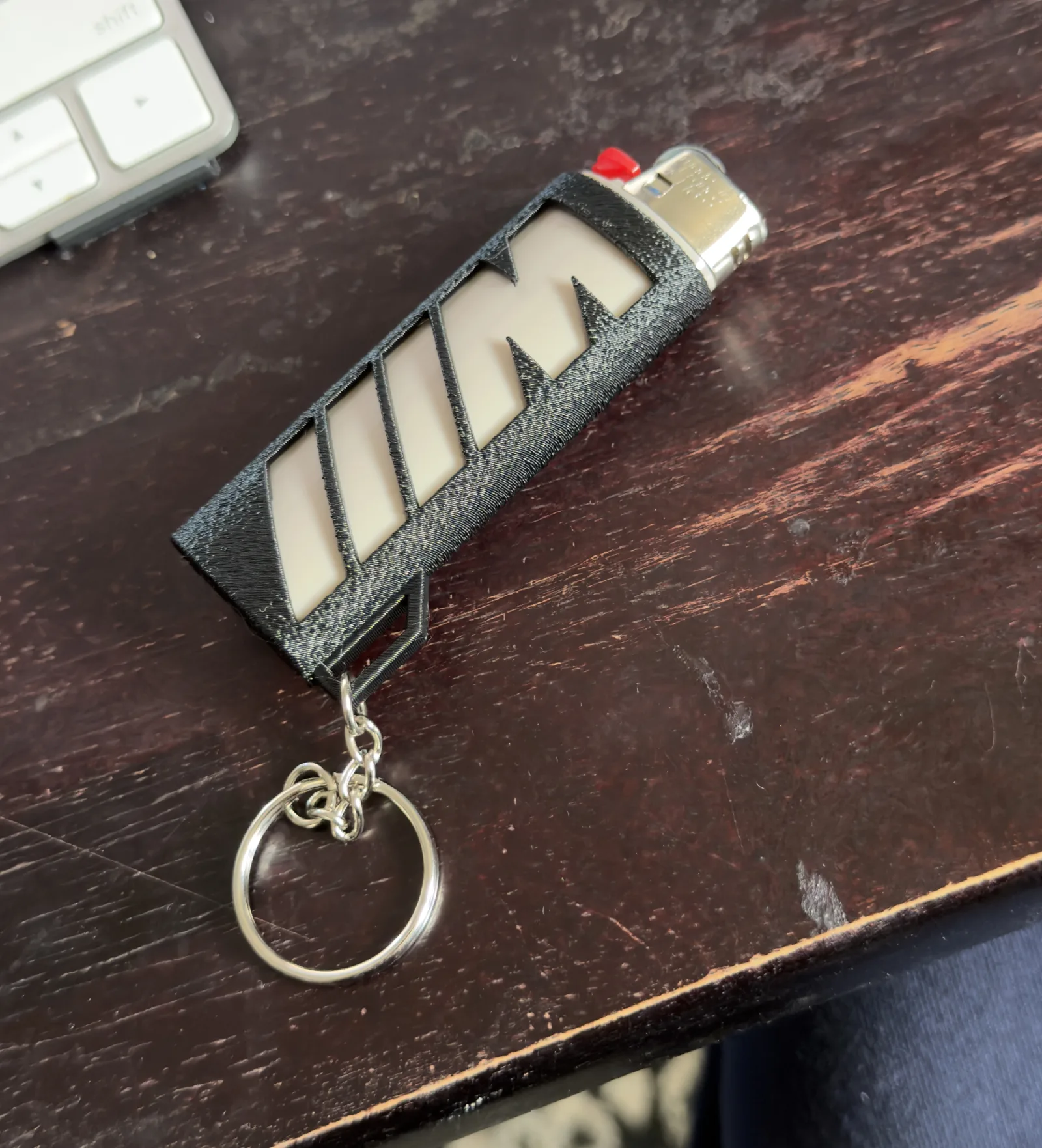 Black BMW M-style lighter case prototype with key ring on a desk