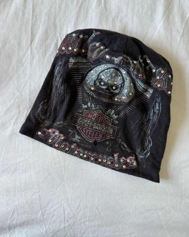 Raw phone photograph of black engine DON beanie on fabric