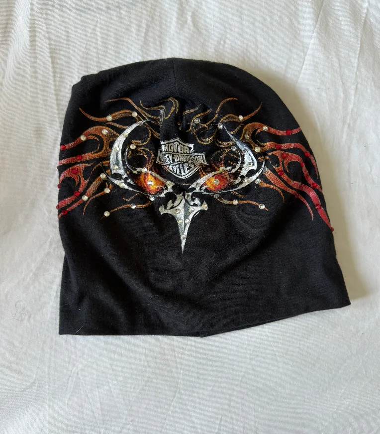 Raw phone photograph of black flame DON beanie on fabric