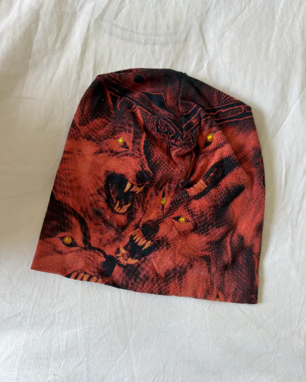Raw phone photograph of red wolf DON beanie on fabric